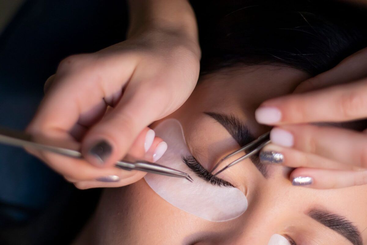 Lash extensions being applied with tweezers, lash by lash