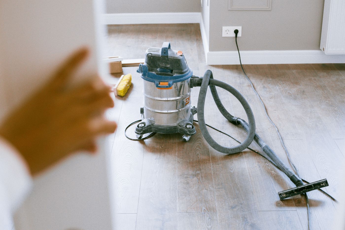 A site vacuum standing on the parquet of a freshly renovated flat