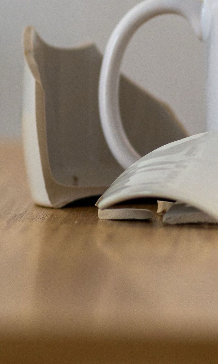 A broken ceramic mug on a wooden table