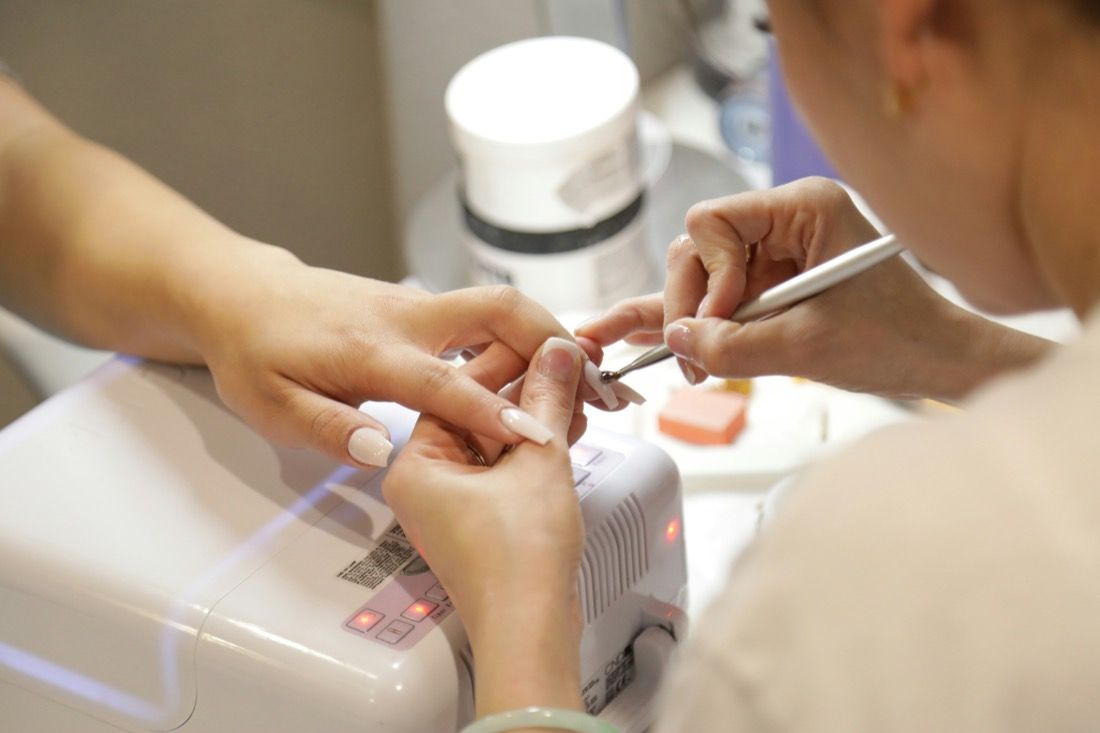 Una manicura en curso bajo una lámpara de uñas.