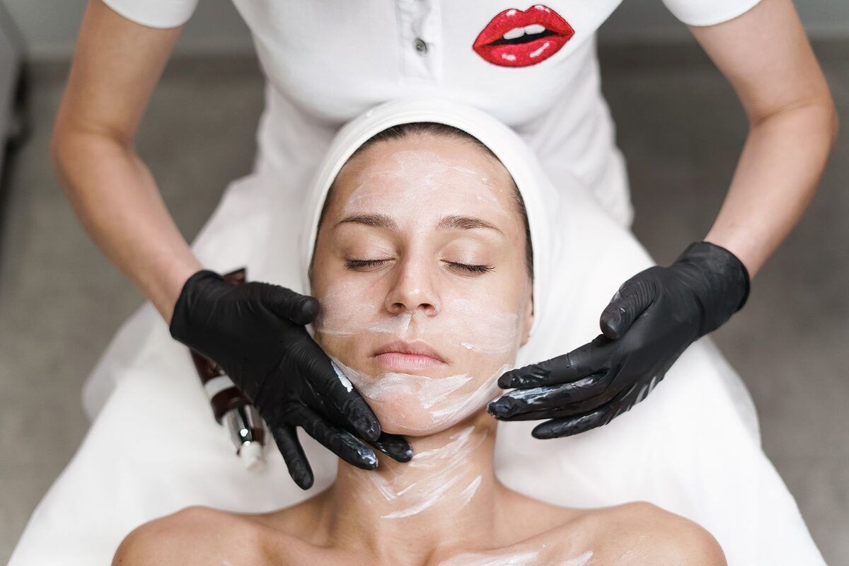Product applied to the face by a gloved beautician
